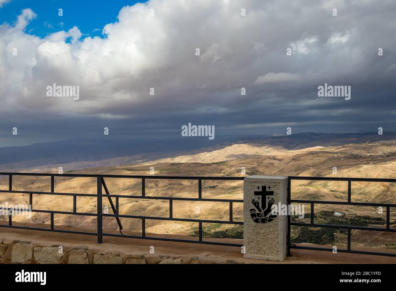 Fence with coat of arms, Memorial Basilica of Moses, Mount Nebo, Jordan. Scenery blurred colorful winter landscape of the Promised Land in the background Stock Photo