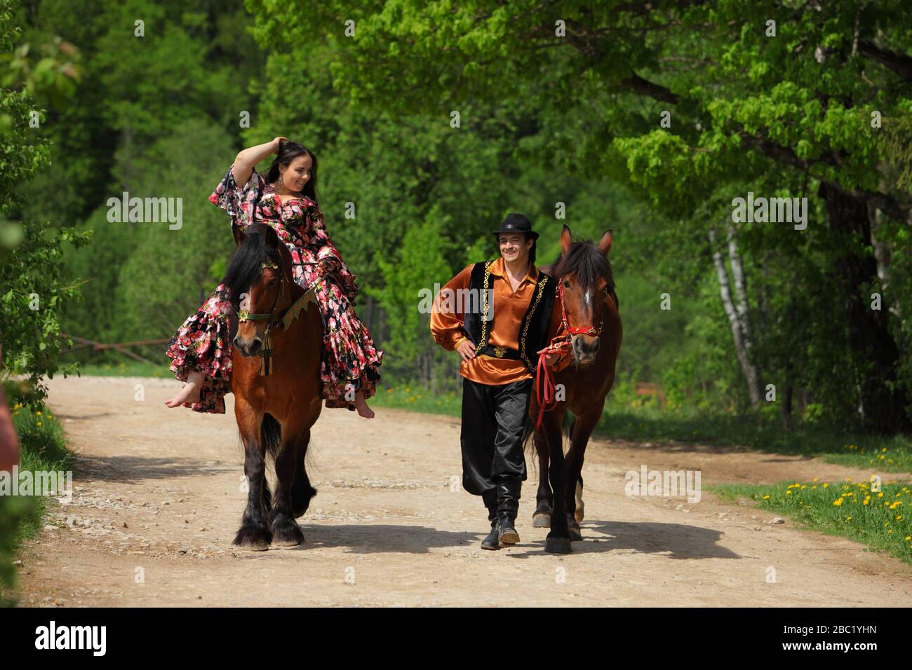 Gypsy pair couple in traditional costumes walks with a horse in summer woods Stock Photo