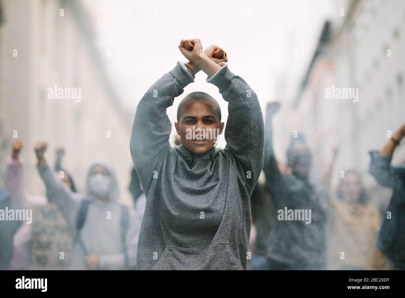 Female activist protesting at a strike with her hands crossed overhead. Woman protesting and giving slogans in the city. Stock Photo