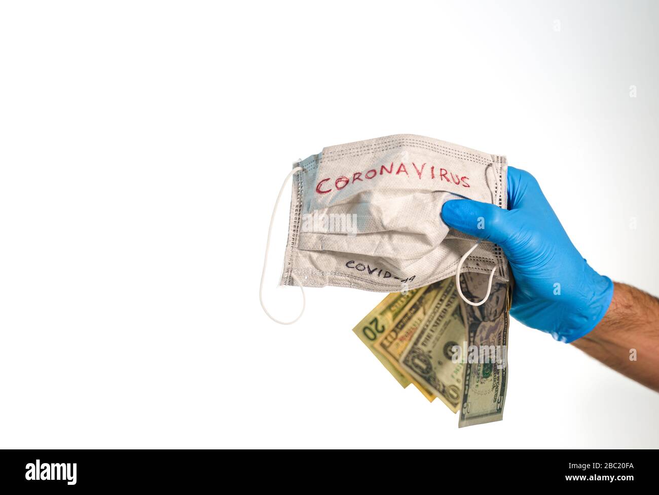 Hand with dollar bills and a face mask with the word coronavirus isolated on white Stock Photo
