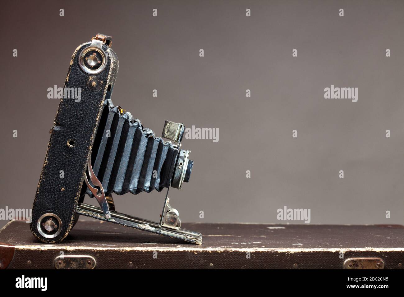 Old vintage camera lying on suitcase on gray background Stock Photo