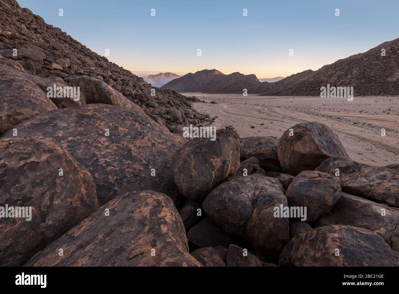 A beautiful arid mountain landscape at sunrise, with fascinating geology and rock formations in the foreground and a mountain range in the background, Stock Photo