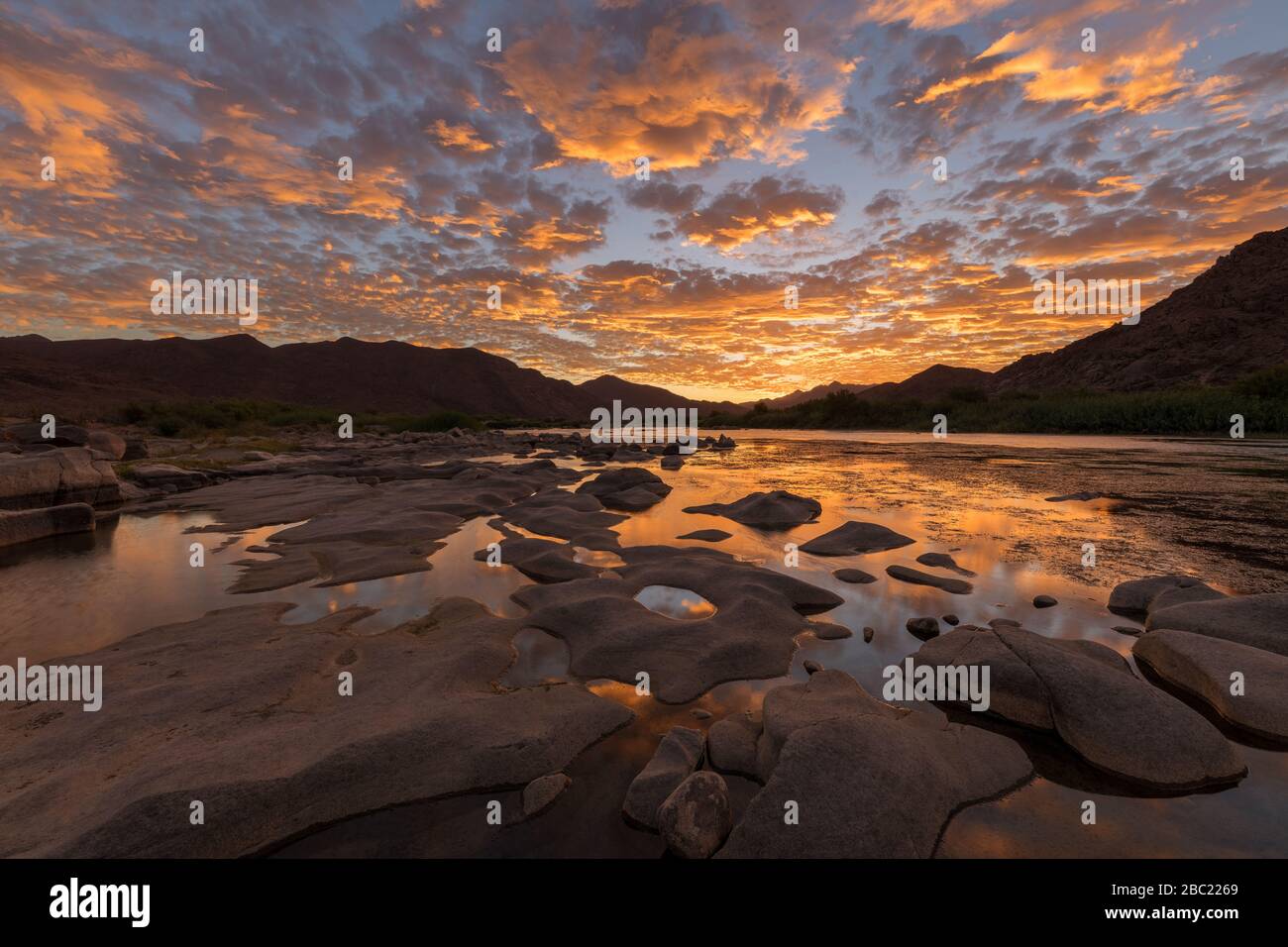 A beautiful landscape of a golden sunset over the mountains and calm ...
