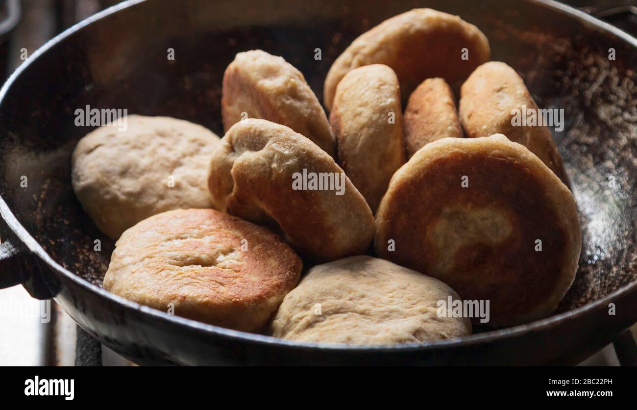 Frying in coconut oil, stove top golden brown whole wheat flour and oatmeal bakes in a pan, popular West Indian tasty delicious healthy breakfast food Stock Photo