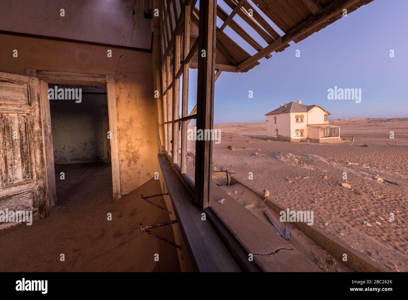 A photograph inside an abandoned house after sunset, with desert sand and a  house visible through broken windows, taken in the ghost town of Kolmansko  Stock Photo - Alamy