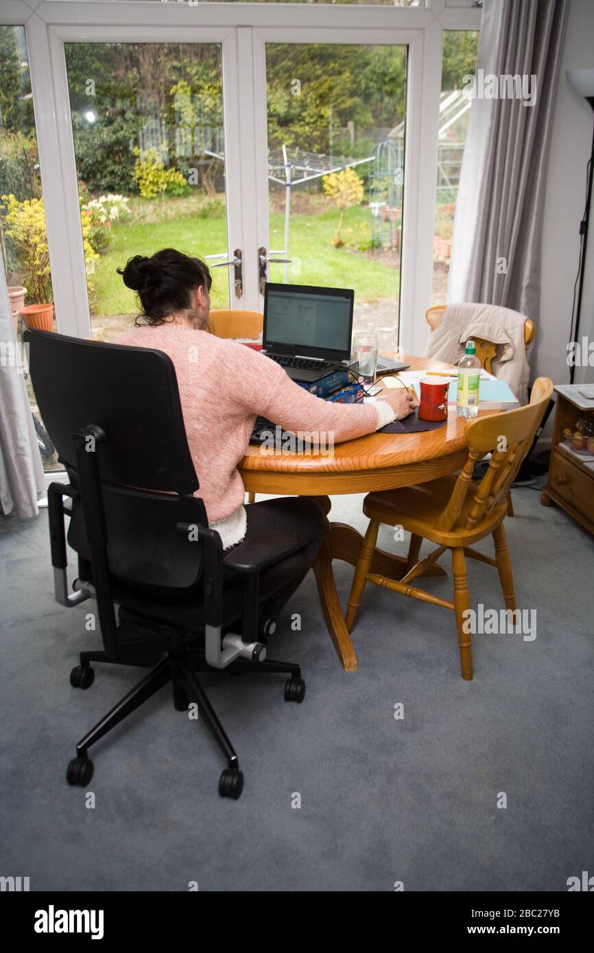 Female office worker sitting at table working from home Stock Photo