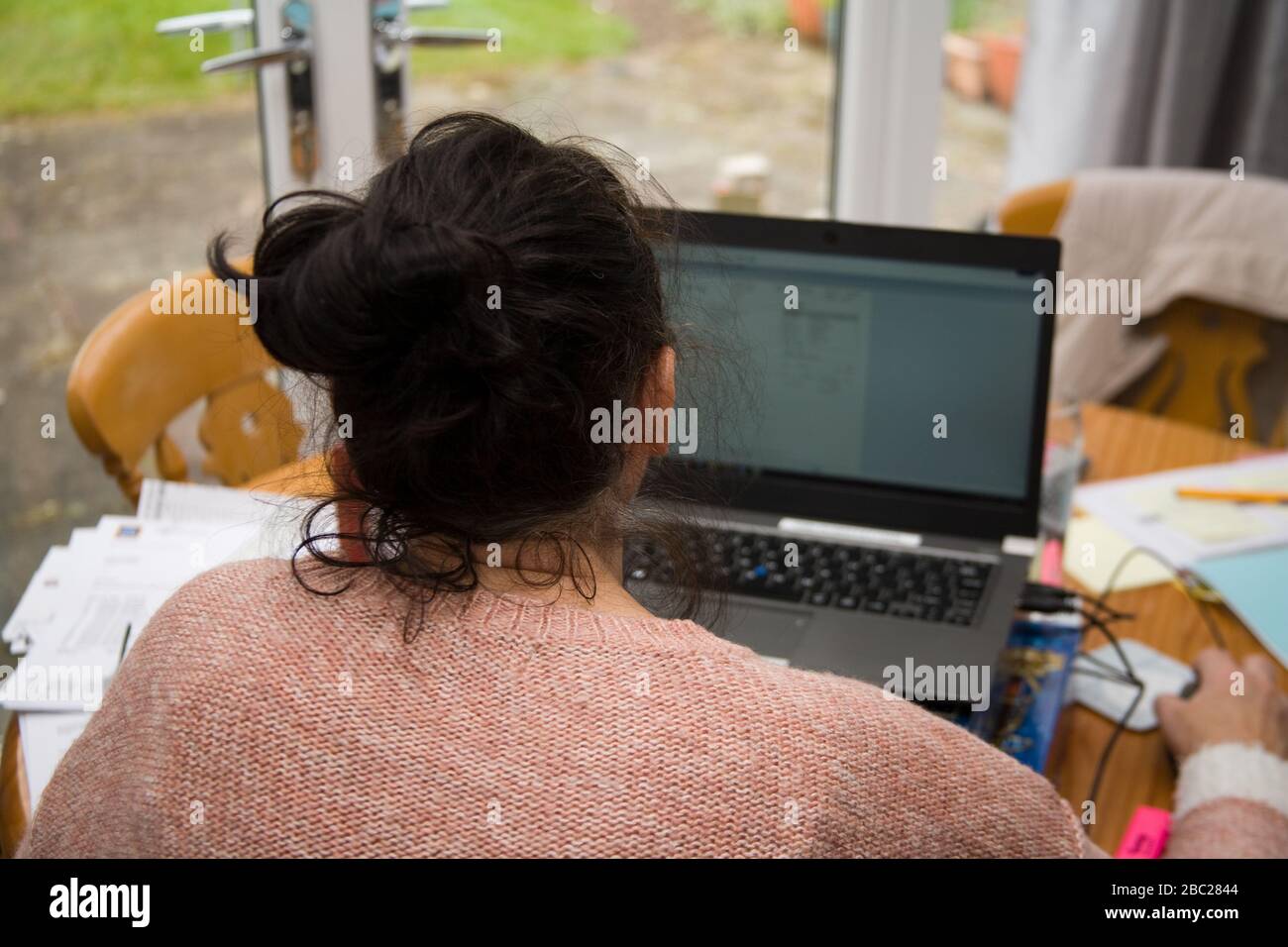 Female office worker sitting at table working from home Stock Photo