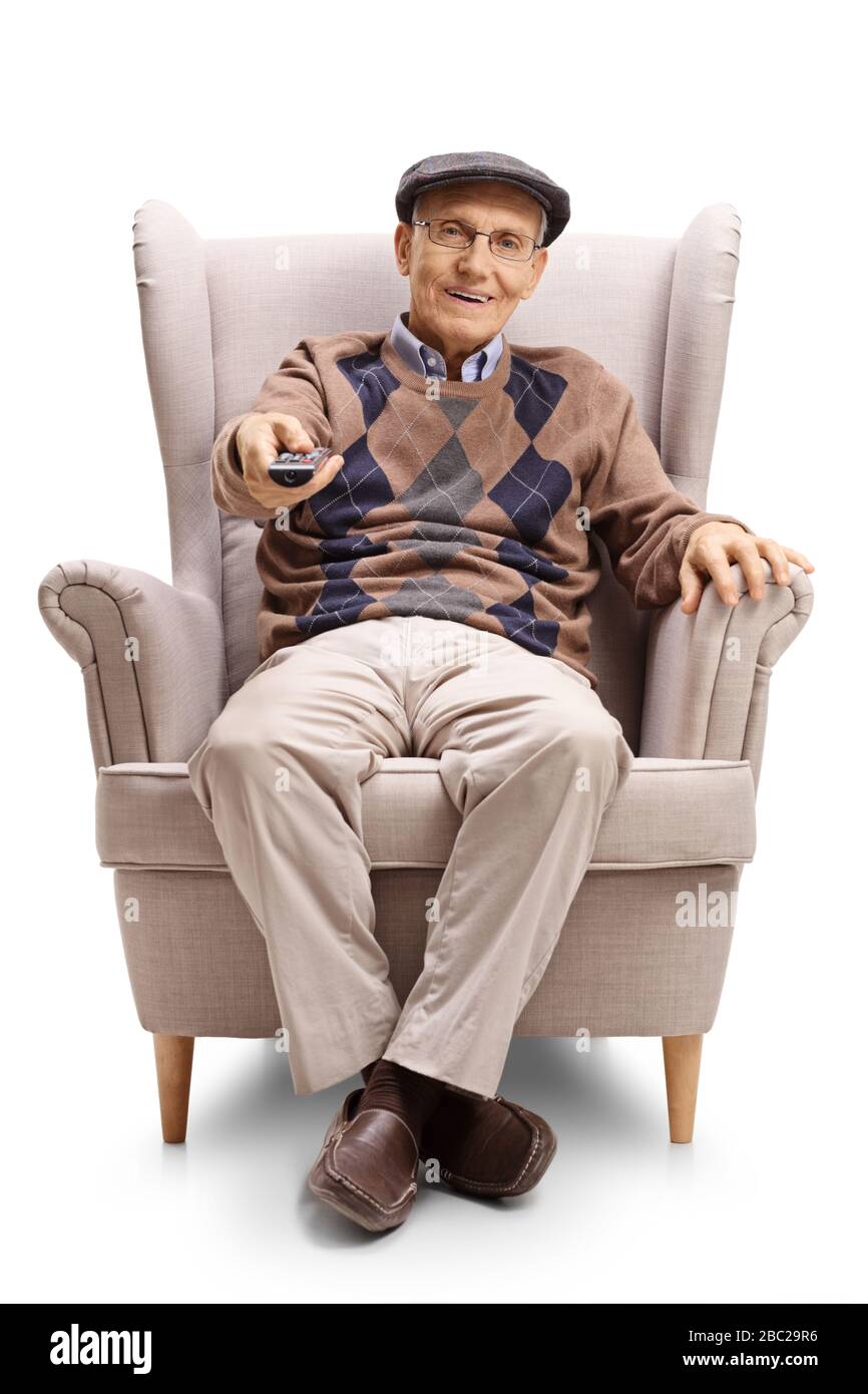 Full length portrait of a senior man sitting in an armchair and using a tv remote control isolated on white background Stock Photo