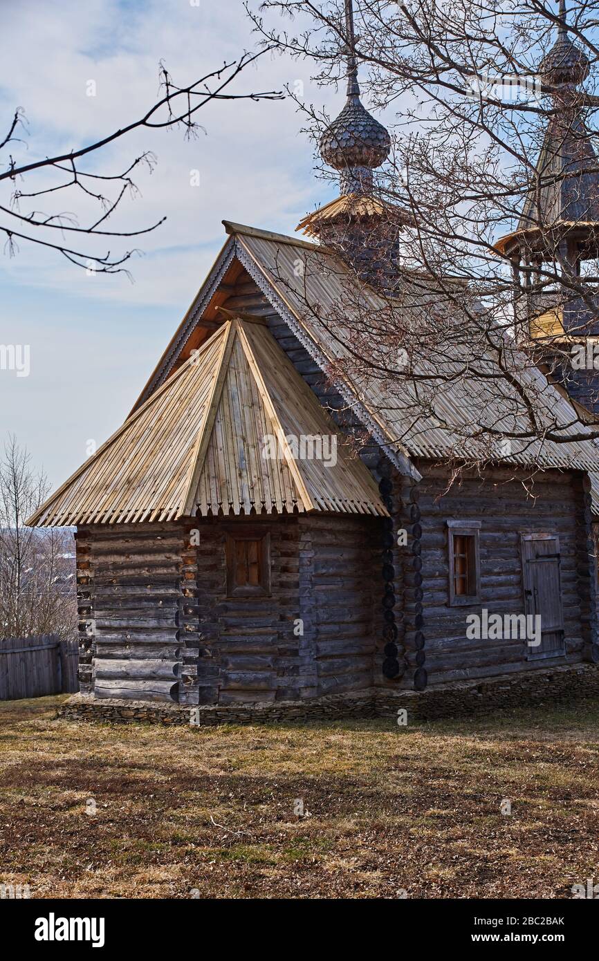 Ancient orthodox temple among trees. Landscape of central Russia. Windows, roof and doors are visible through branches. The village of Big Boldino. Stock Photo