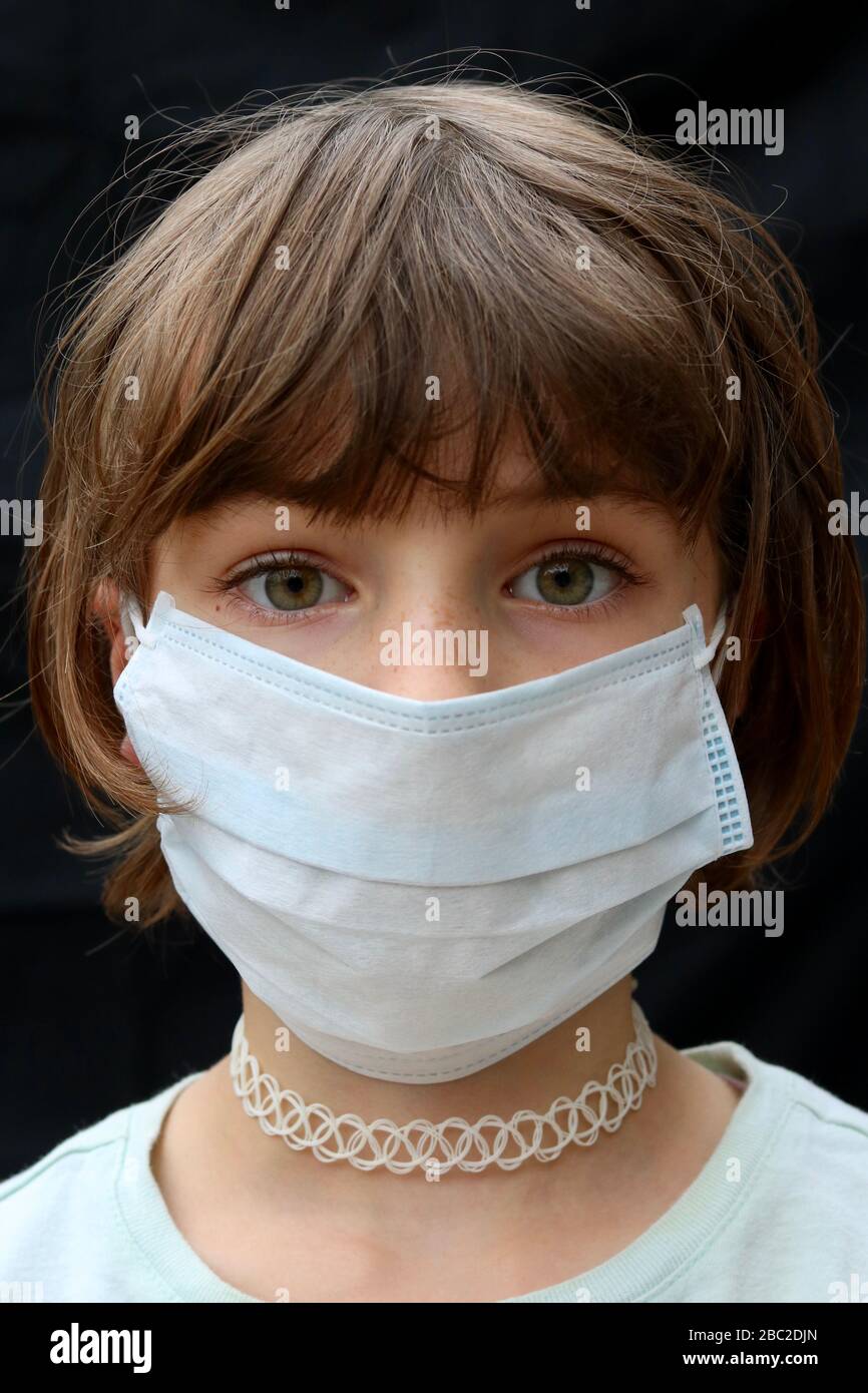 Portrait of a little girl looking scared wearing a face mask Stock Photo