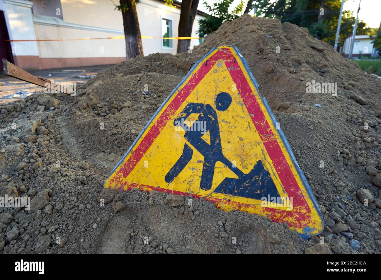 Road work sign placed on a pile of dug up land in the middle of a road