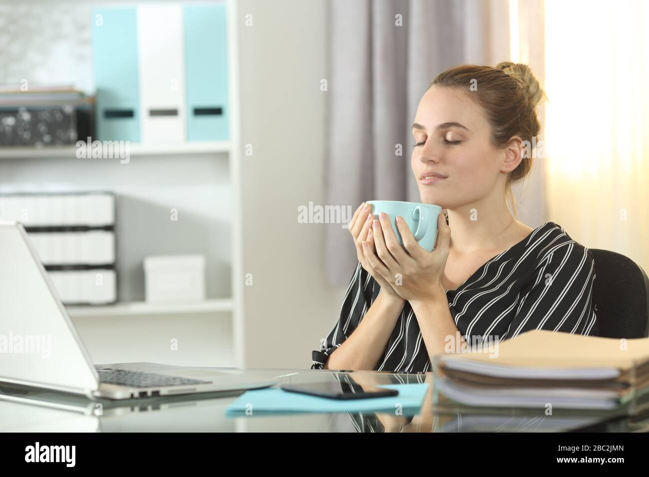 Relaxed entrepreneur resting drinking coffee sitting at homeoffice Stock Photo