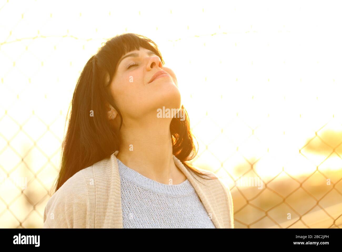 Happy adult woman breathing deeply fresh air at sunset standing in the street Stock Photo