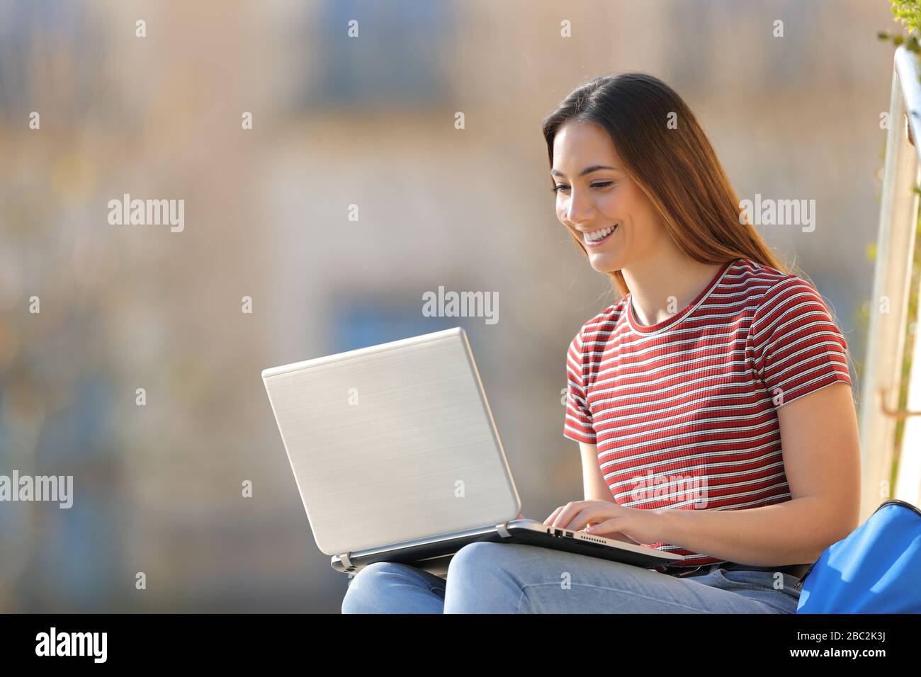Happy student e-learning using laptop in a university campus a sunny ...