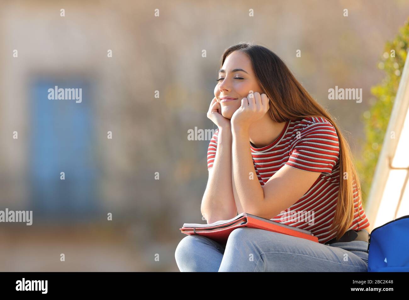 Happy student relaxing sitting in a campus a sunny day Stock Photo