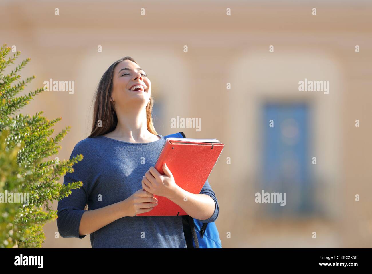 Happy student breathing fresh air and laughing standing in an university campus Stock Photo