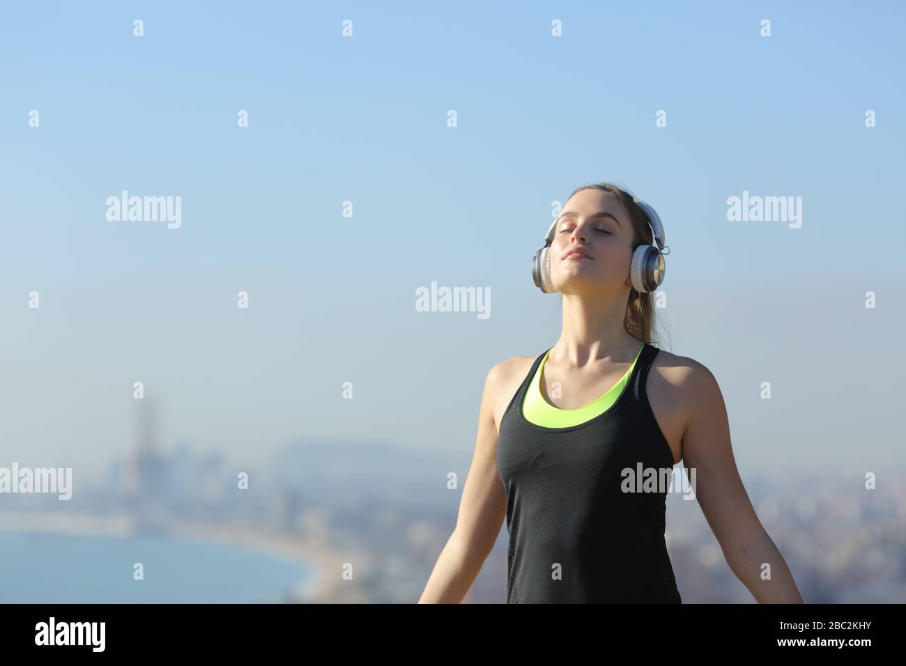 Relaxed runner wearing headphones breathing fresh air outdoors in a city outskirts Stock Photo