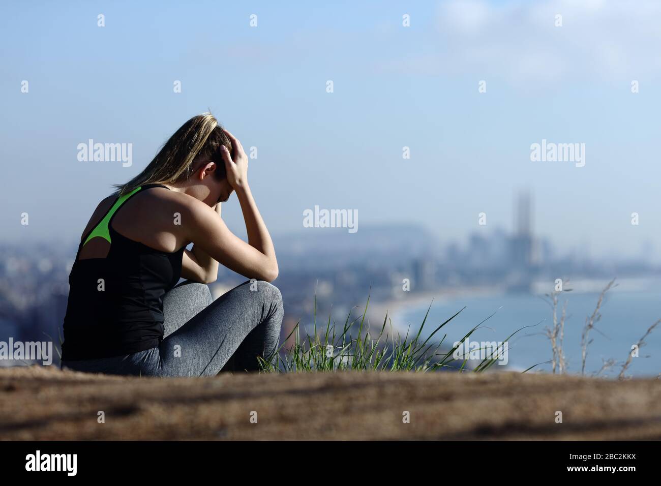 Sad runner complaining sitting alone in city outskirts Stock Photo