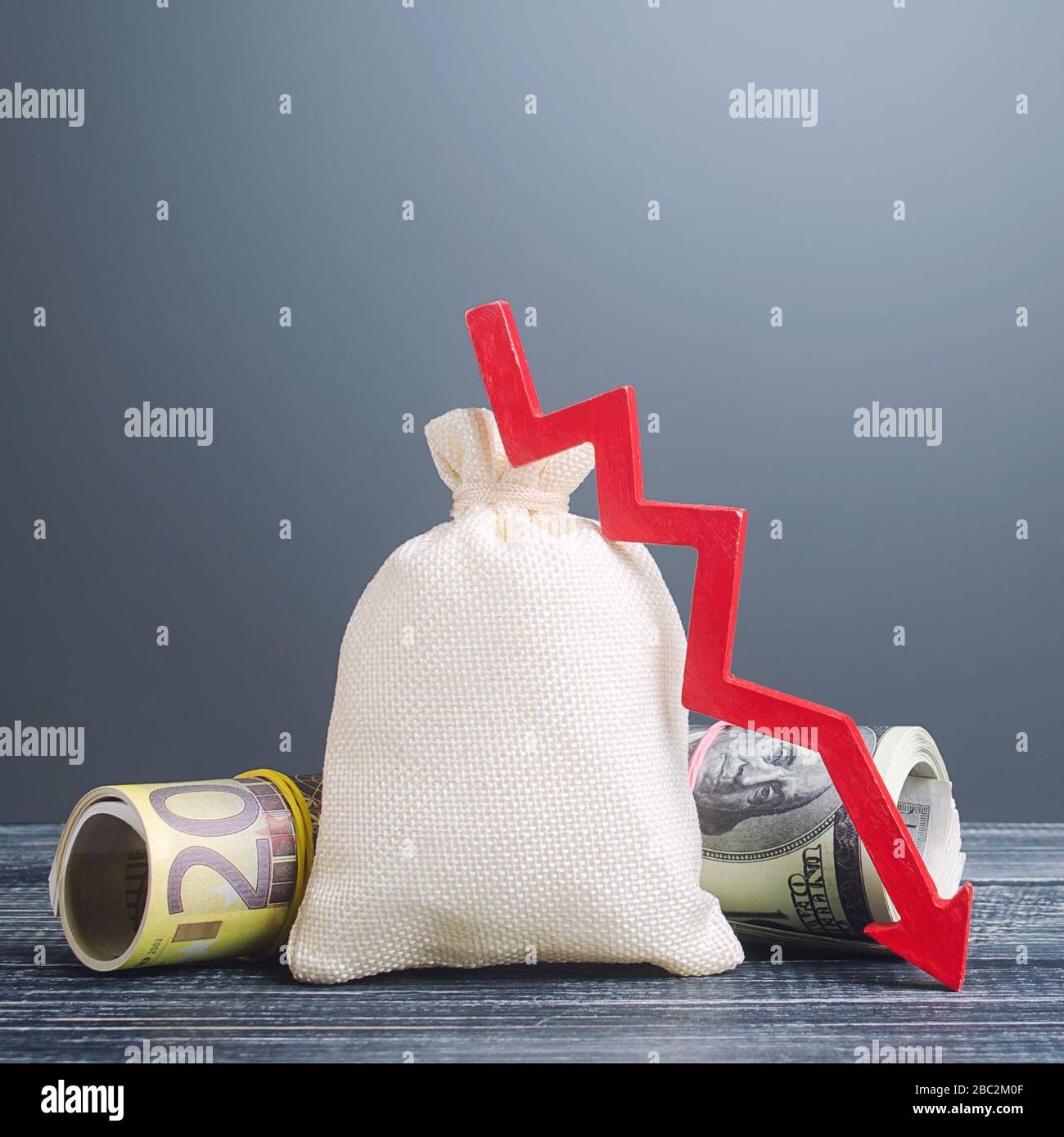 Big money bag and red arrow down. Economic difficulties. Capital flight, high risks. Costs expenses. Stagnation, declining business activity, falling Stock Photo