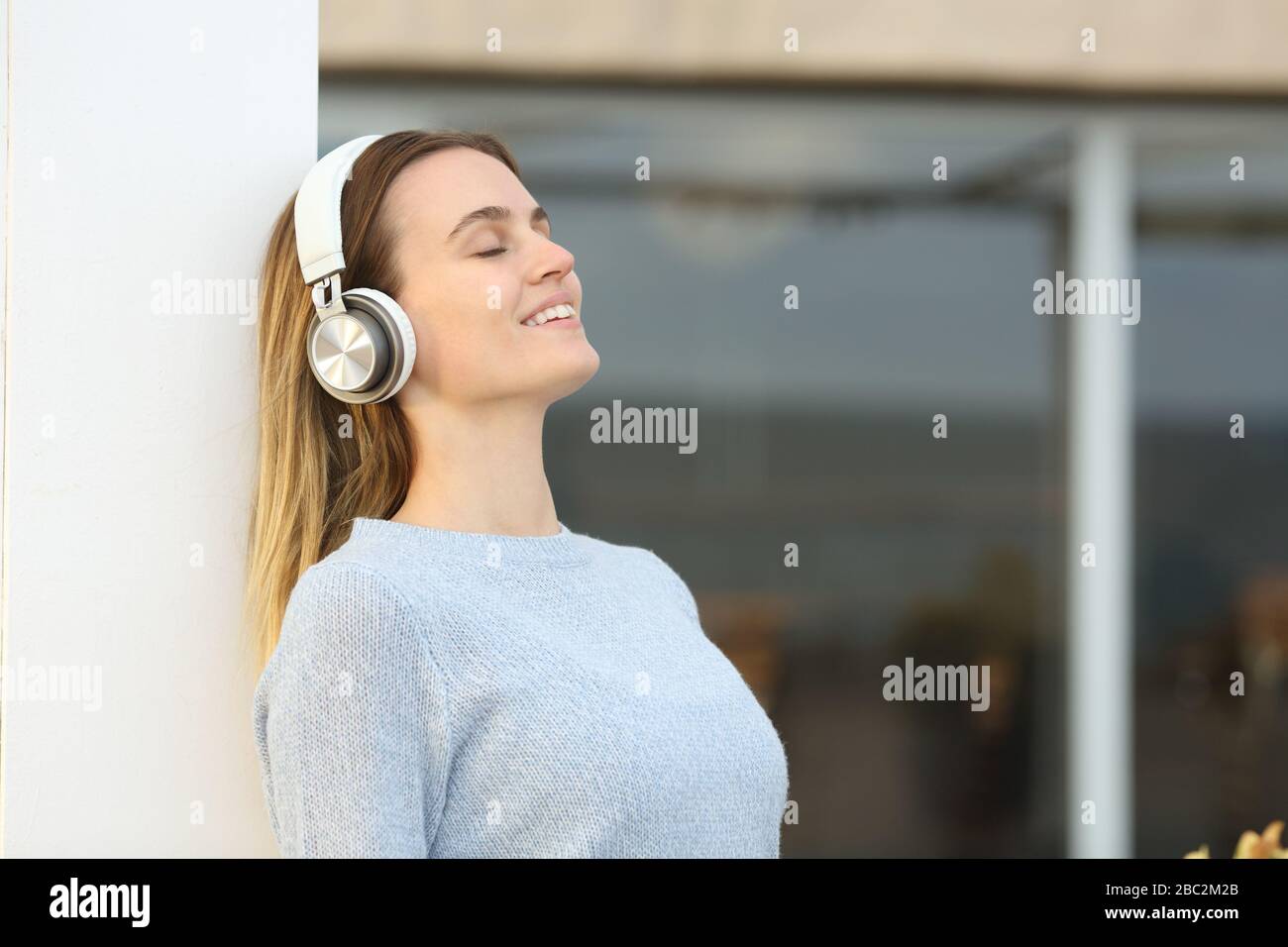 Relaxed young woman with headphones breathing fresh air on a hotel terrace Stock Photo