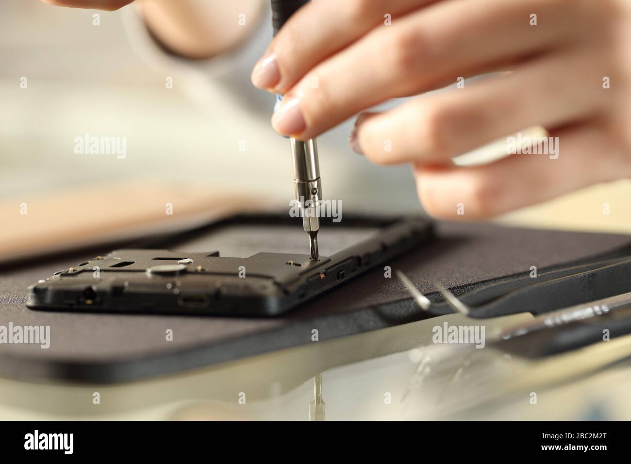 Close up of woman hands removing screws on a smart phone on a desk Stock Photo