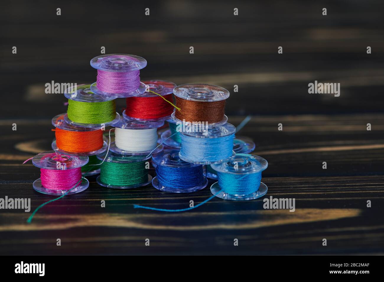 macro of colored cotton thread on yarn bobbins on brown wooden background in a stack Stock Photo