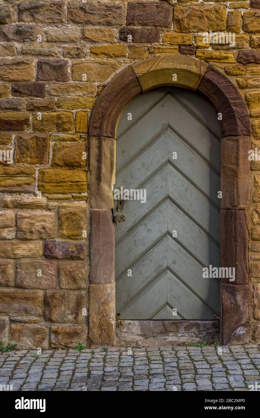 sandstone historic city wall with wooden door and door frame with sandstone round arch carved with special lock Stock Photo