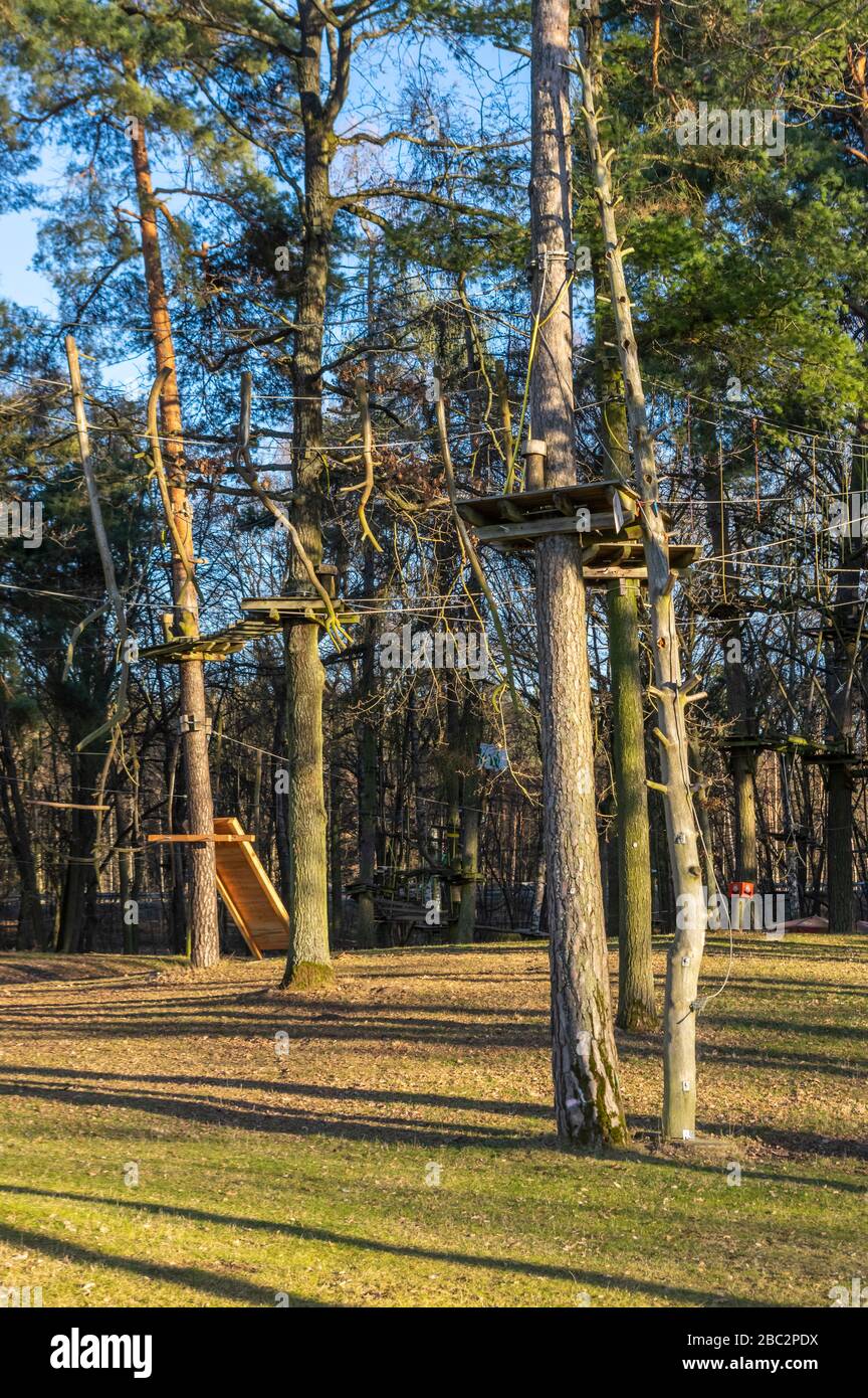 Climbing garden, high ropes course in the forest with various climbing elements and safety ropes between the individual trees and benches to rest Stock Photo