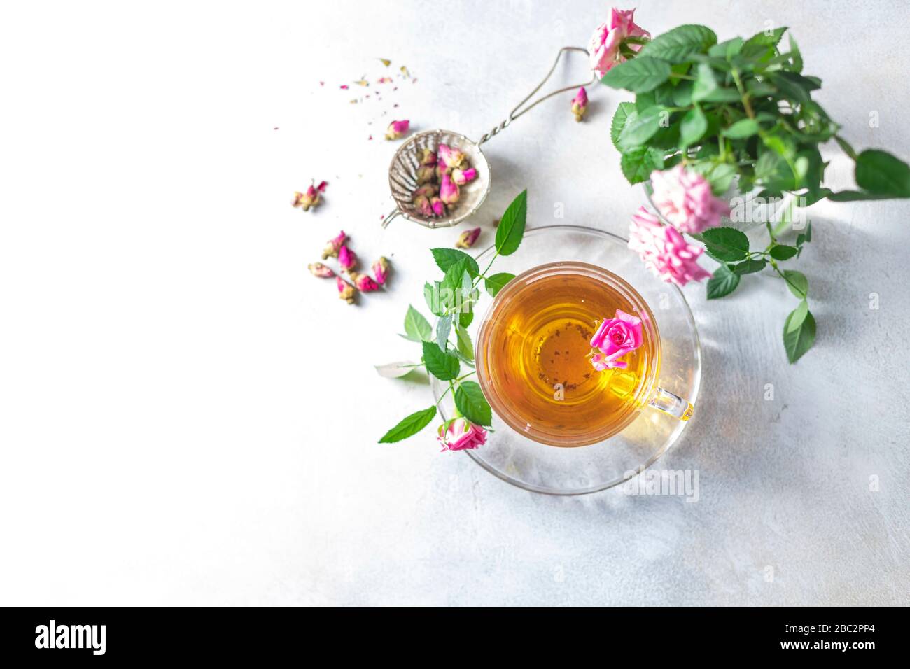 Pink tea buds, a glass cup and vintage strainer. Selective focus, copy space. Top view. Stock Photo