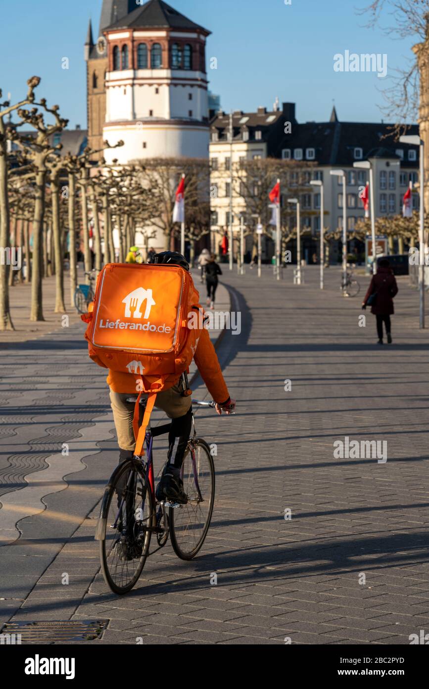 Delivery service Lieferando.de, delivery messenger with bicycle on the banks of the Rhine in DŸsseldorf, Germany, Stock Photo
