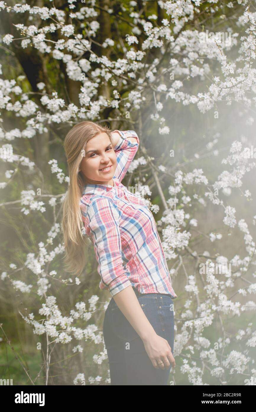 Beautiful girl in flowering trees in early spring. Bright sun and ...