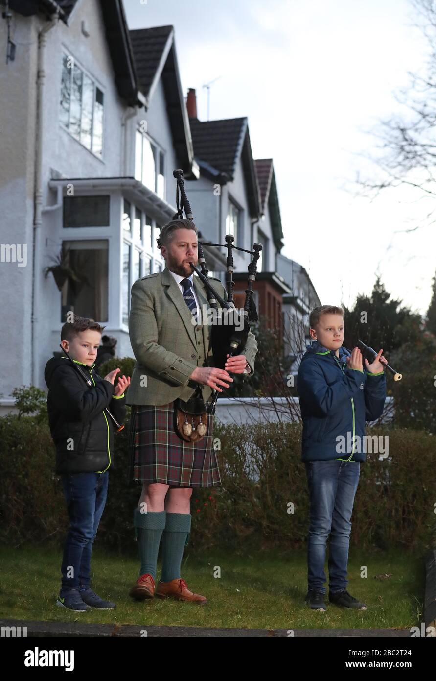 Finlay MacDonald plays the pipes at his home in Glasgow alongside sons Elliott, ten, and Fionn, eight to salute local heroes during Thursday's nationwide Clap for Carers NHS initiative to applaud NHS workers fighting the coronavirus pandemic. Stock Photo