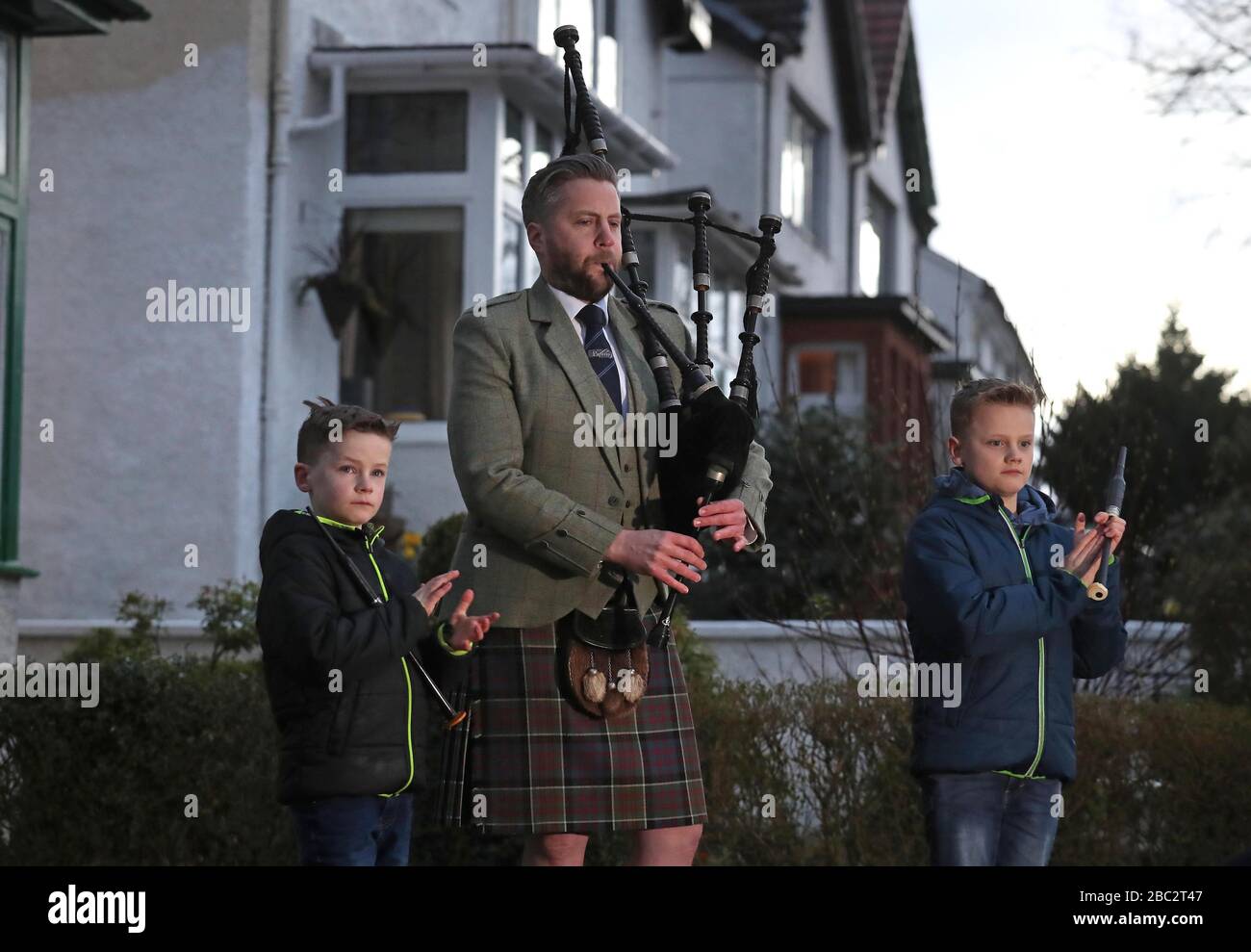 Finlay MacDonald plays the pipes at his home in Glasgow alongside sons Elliott, ten, and Fionn, eight to salute local heroes during Thursday's nationwide Clap for Carers NHS initiative to applaud NHS workers fighting the coronavirus pandemic. Stock Photo