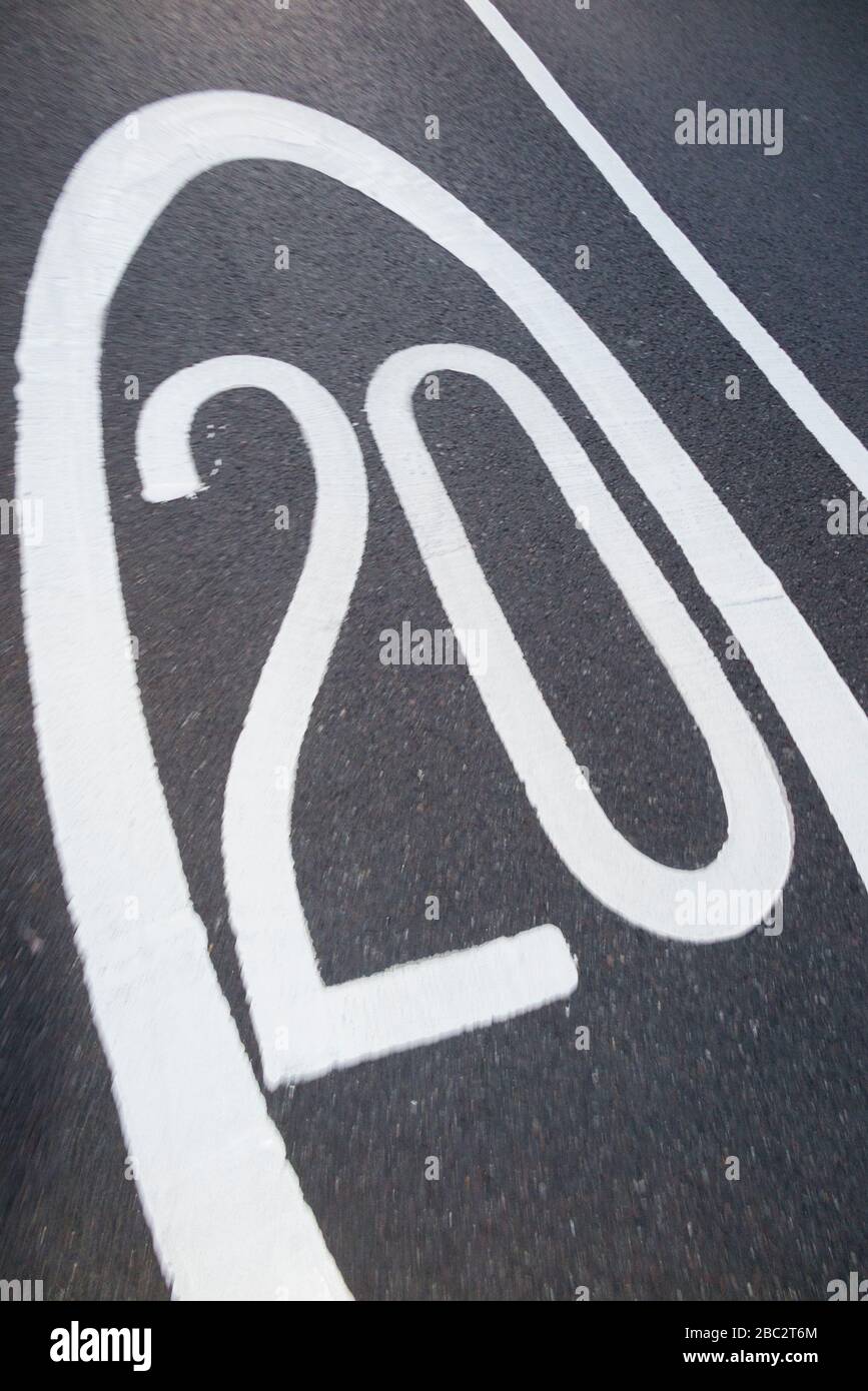 Newly painted  20 mph / twenty miles per hour speed limit road marking / road markings restriction sign / signs on the road / roads surface of tarmac. UK. (116) Stock Photo