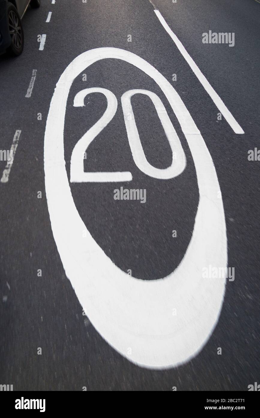 Newly painted  20 mph / twenty miles per hour speed limit road marking / road markings restriction sign / signs on the road / roads surface of tarmac. UK. (116) Stock Photo