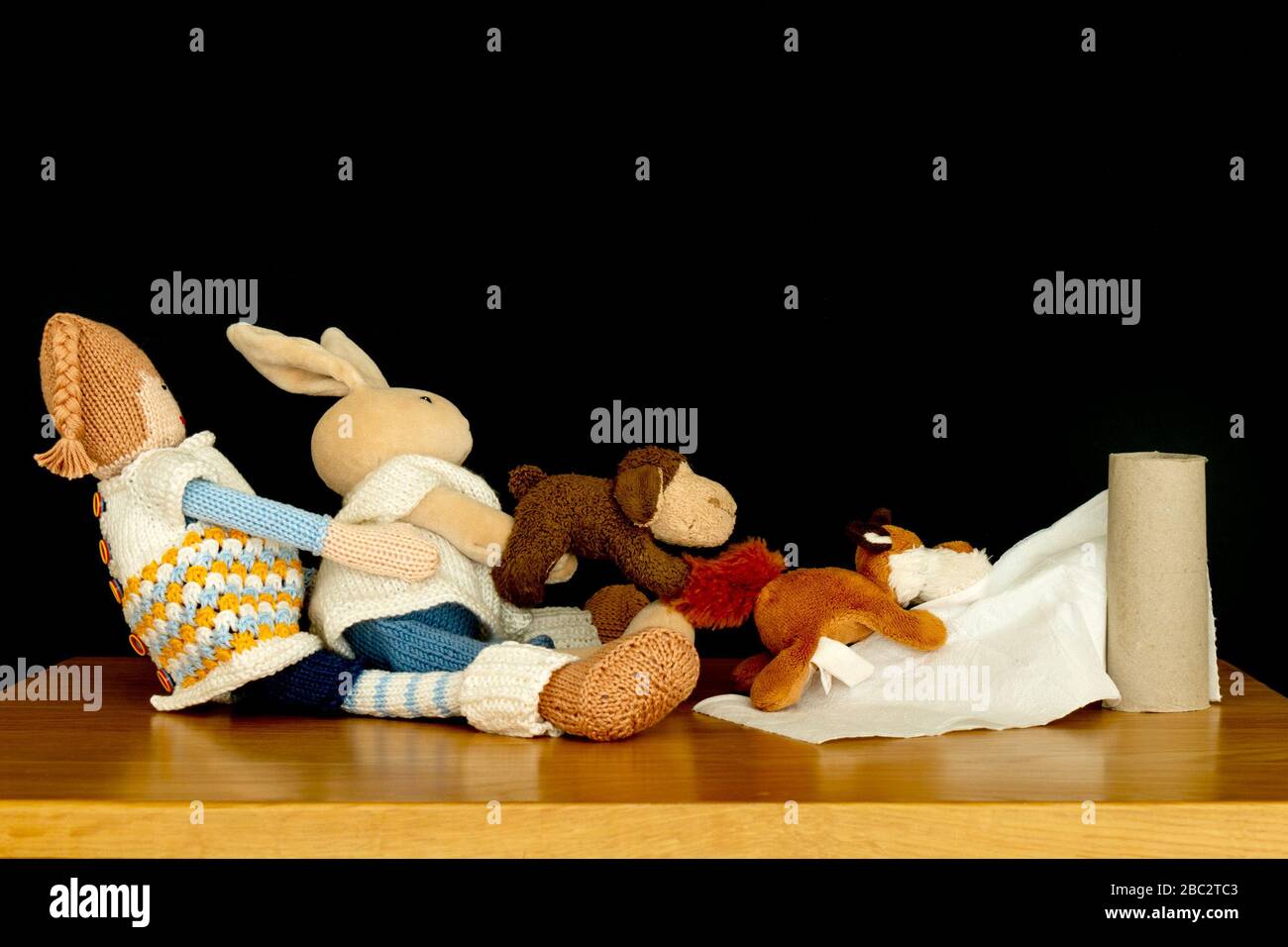 Concept image illustrating toilet roll shortage as several cuddly toys try to hang on the last pieces of toilet paper Stock Photo