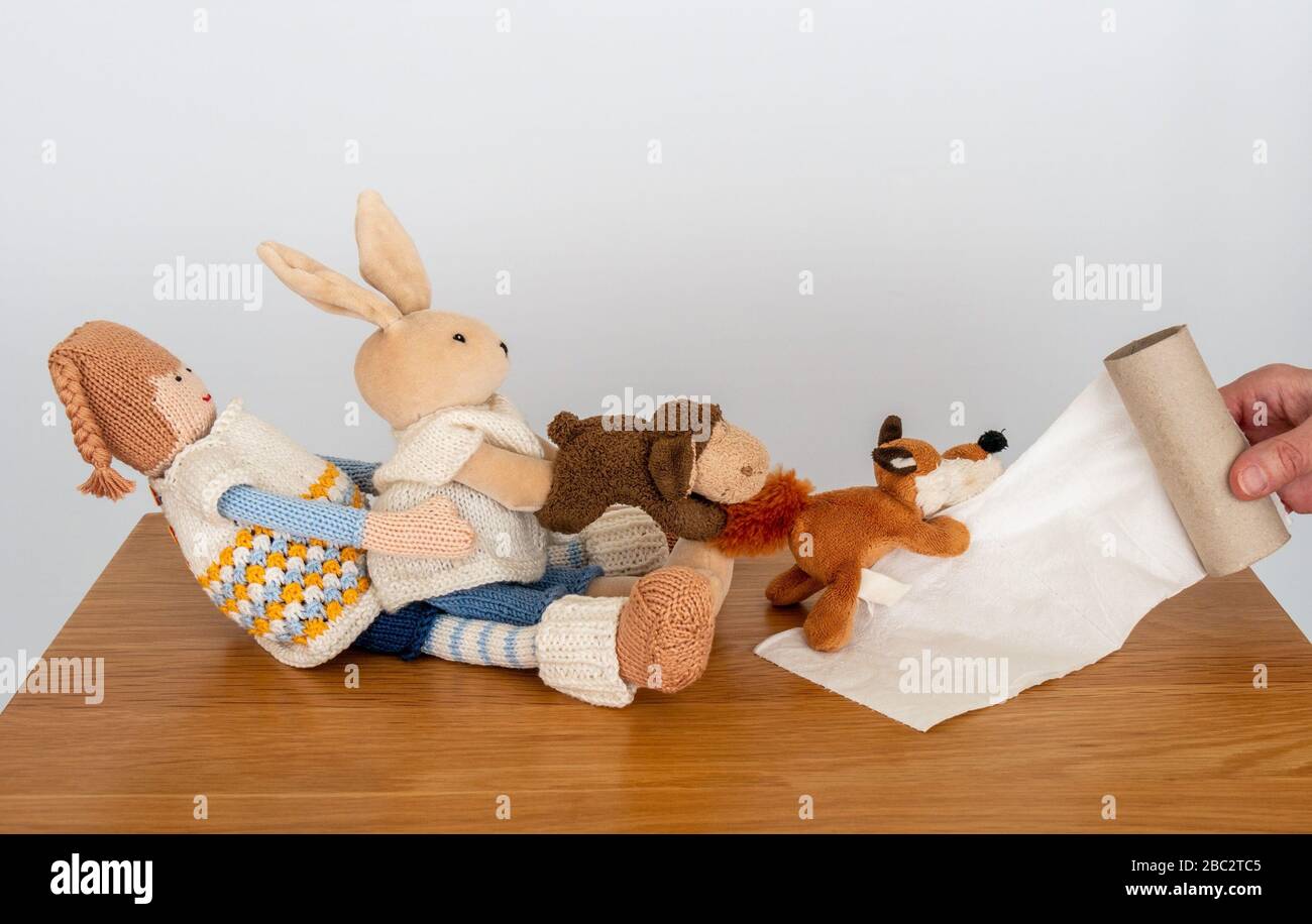 Concept image illustrating toilet roll shortage as several cuddly toys try to hang on the last pieces of toilet paper Stock Photo