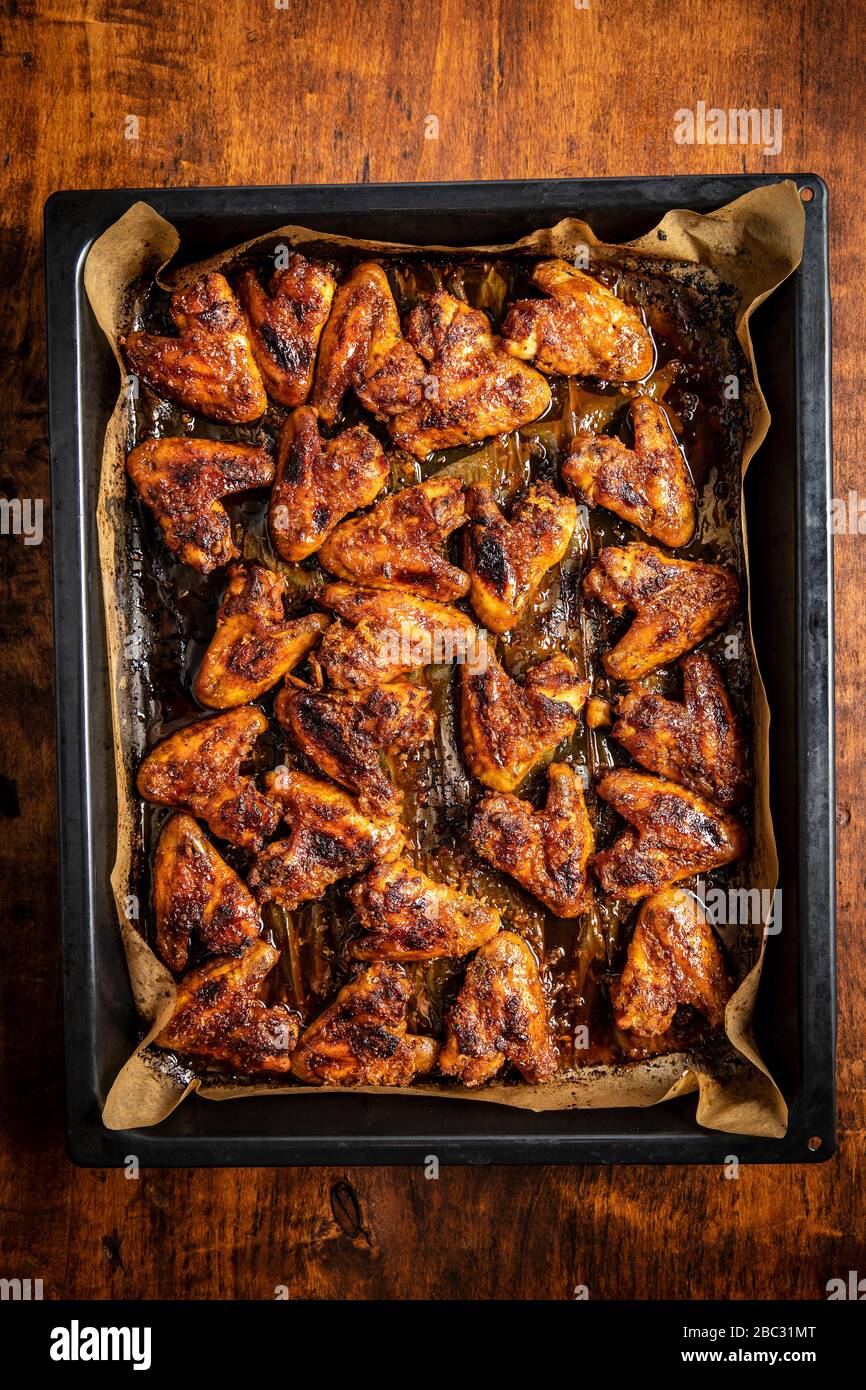 Grilled chicken wings in barbecue sauce in baking tray on wooden table. Top view. Stock Photo