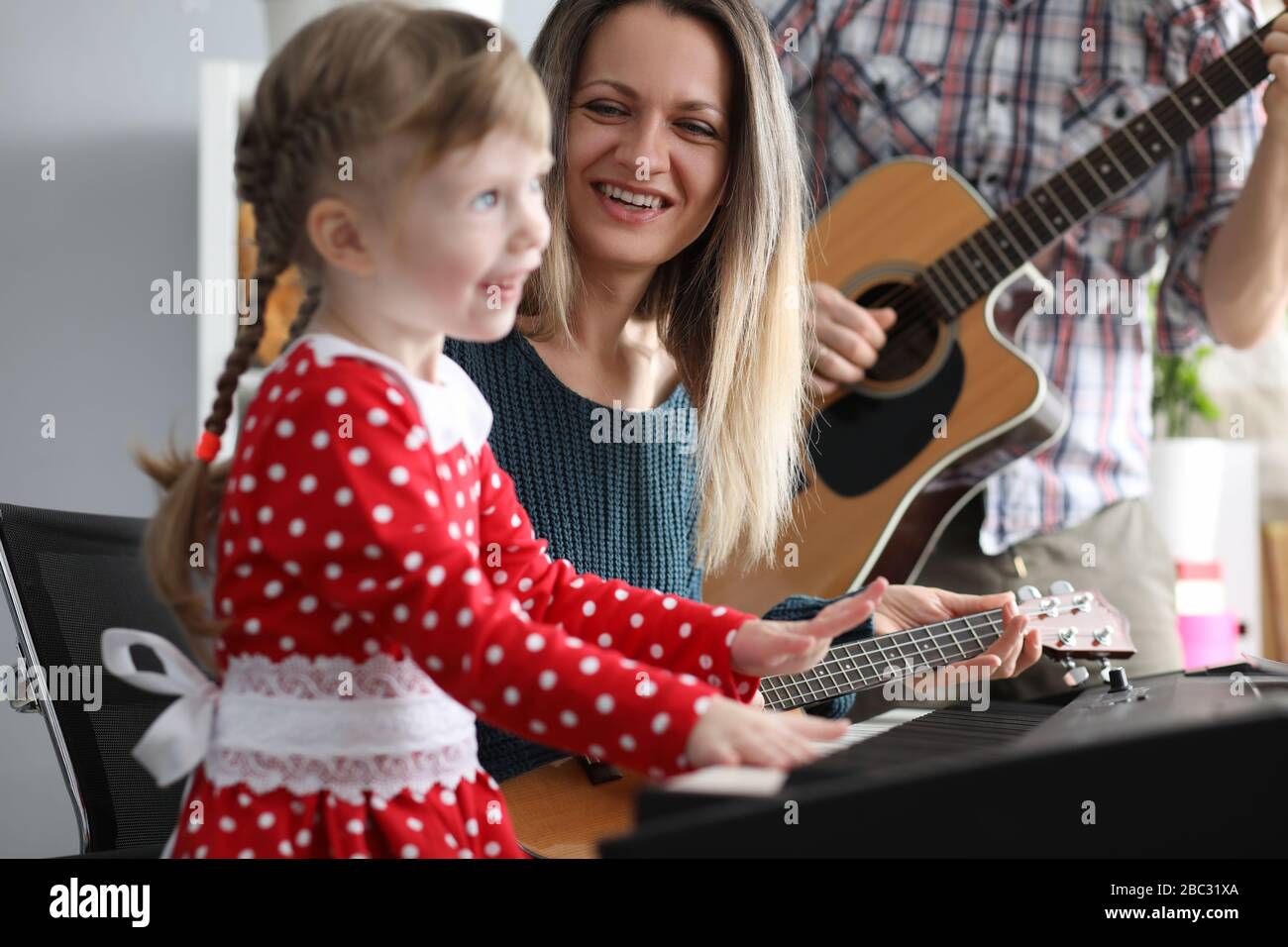 Parents play guitars, daughter on synthesizer Stock Photo