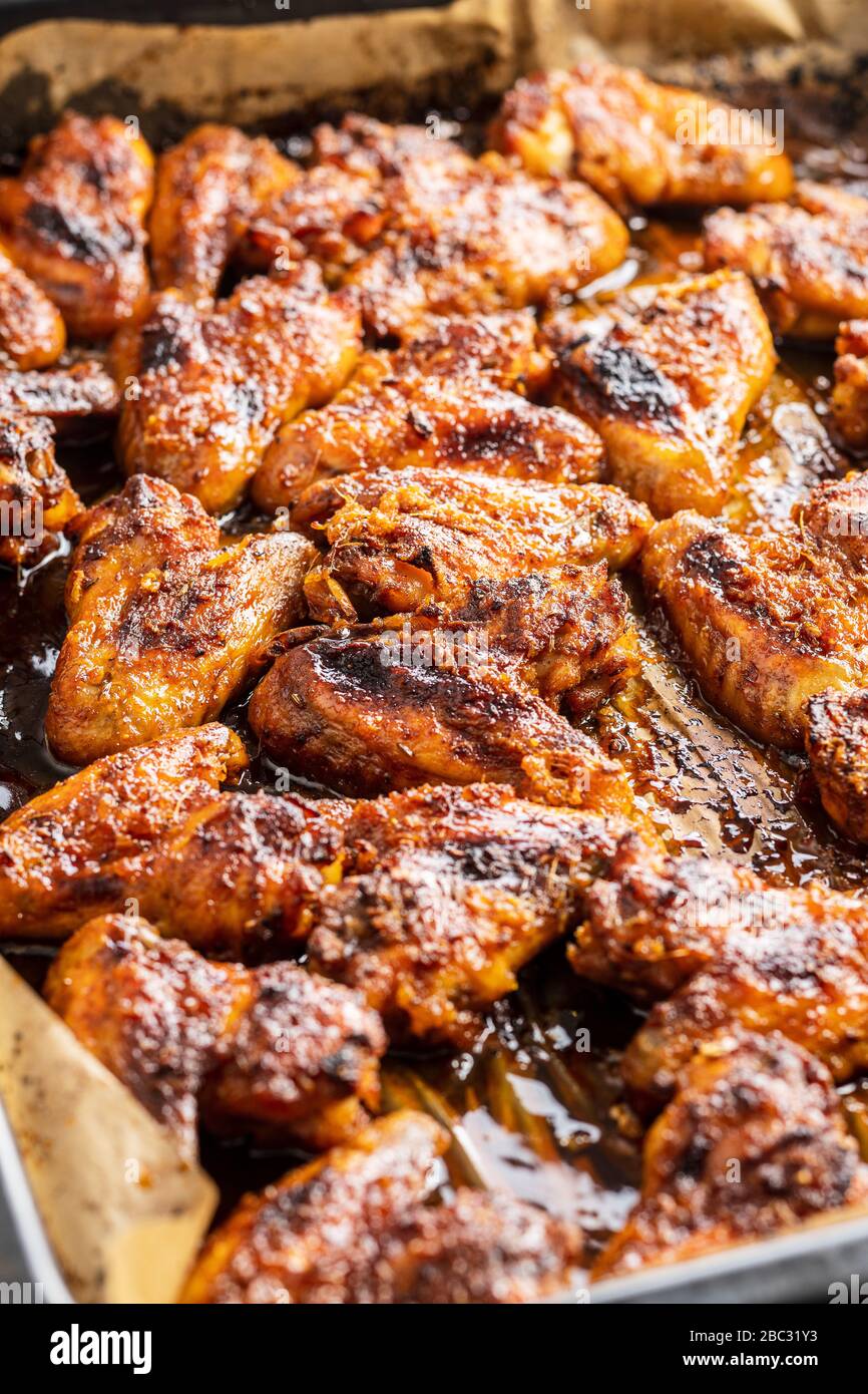 Grilled chicken wings in barbecue sauce on baking paper in baking tray. Stock Photo