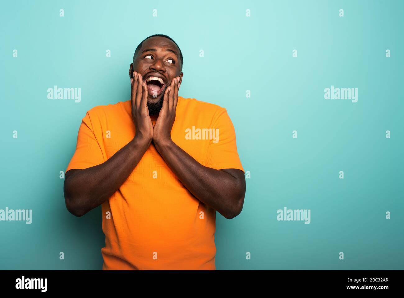 Joyful and happy afro guy over cyan background Stock Photo
