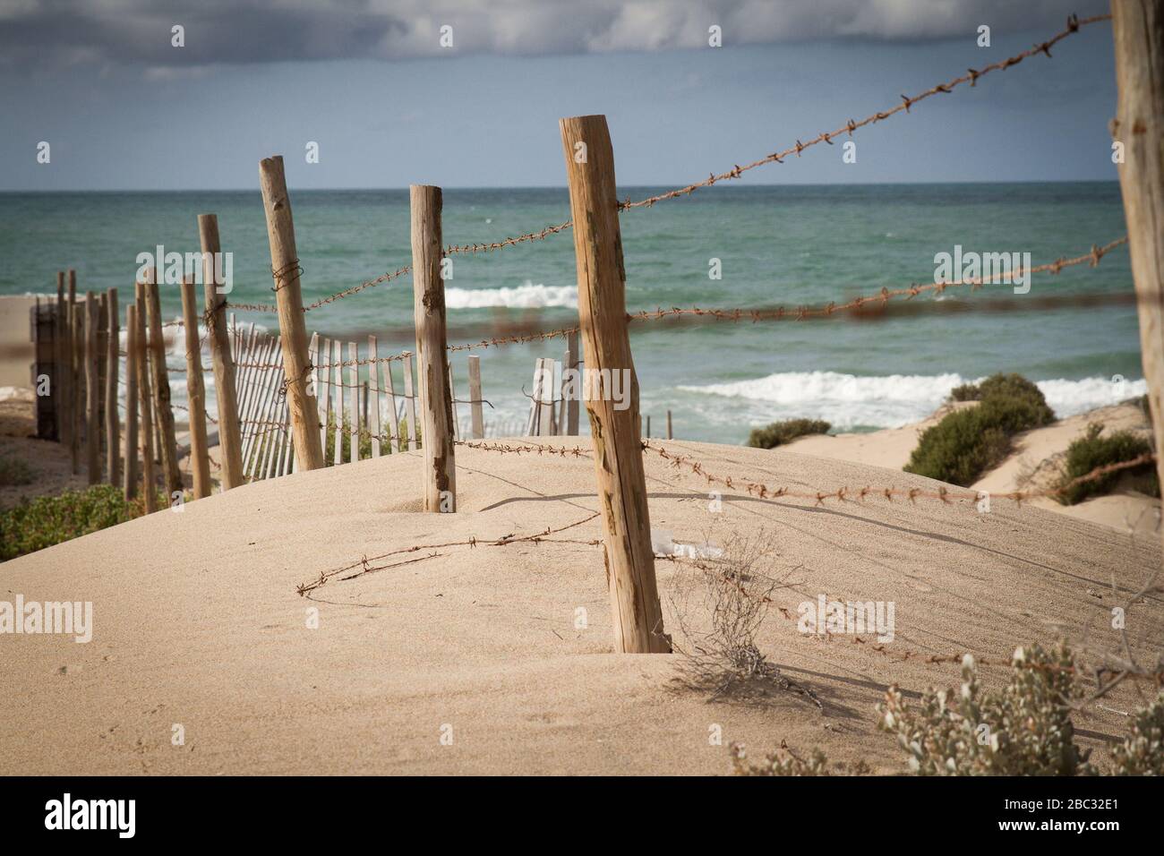 Fence posts held together with barbed wire stick out of a sand dune overlooking the Sea of Cortez near Puerto Penasco, Sonora, Mexico. Stock Photo