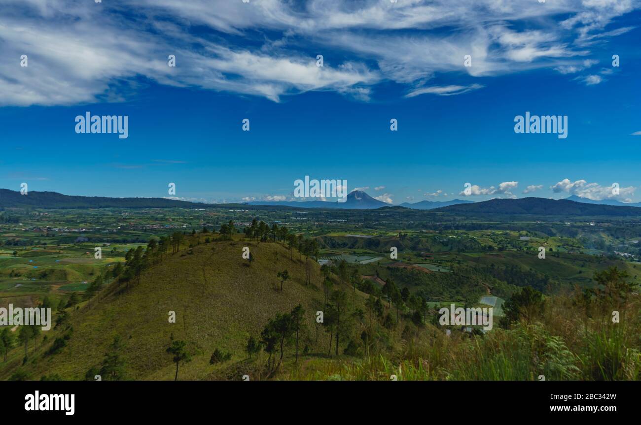 Sinabung volcano mountain very active and dangerous visible in distance beyond karo batak highlands in North Sumatra, Indonesia Stock Photo