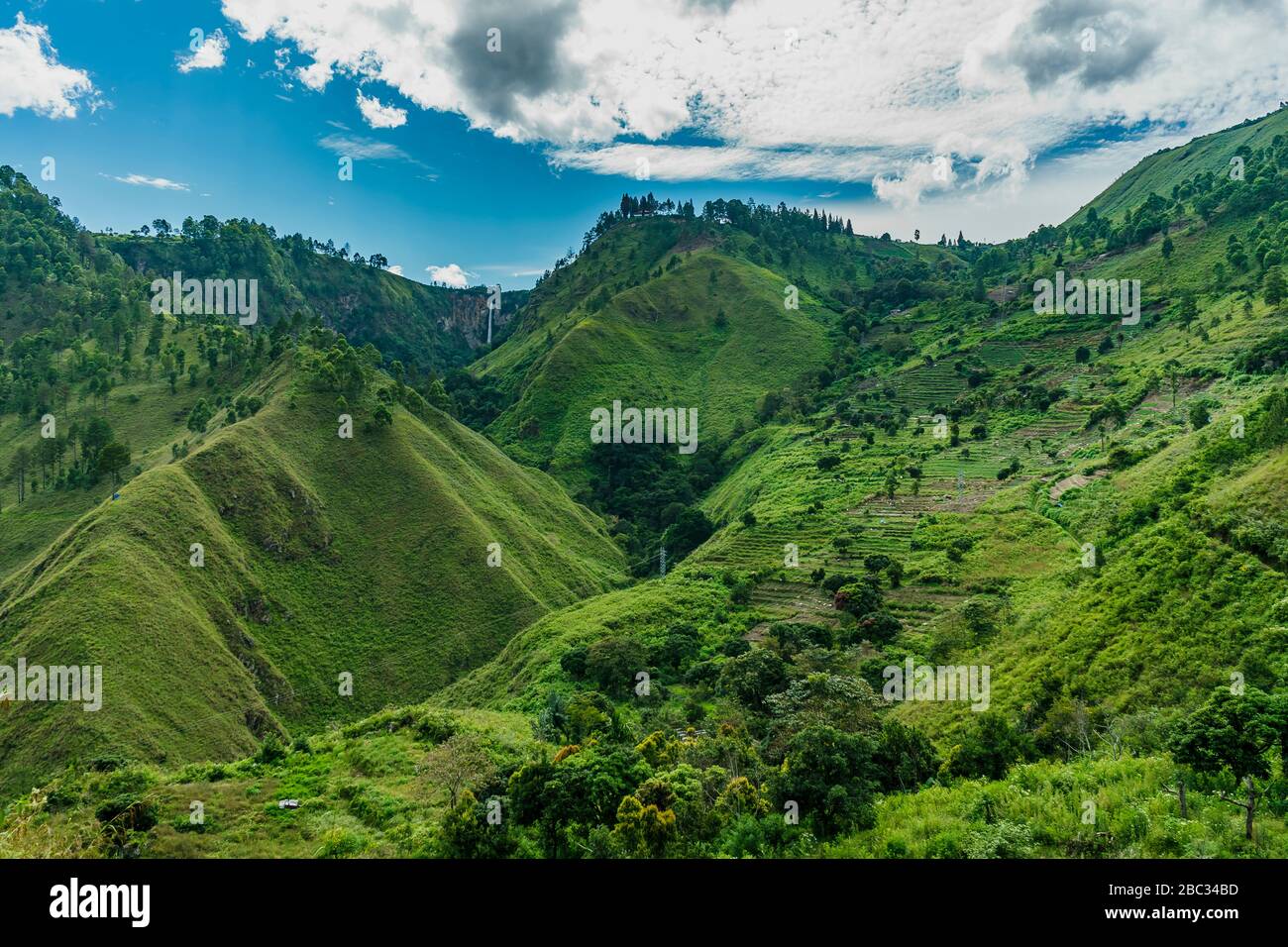 Vibrant lake toba slopes with one of the highest waterfalls in Indonesia Sipiso visible in distance Stock Photo