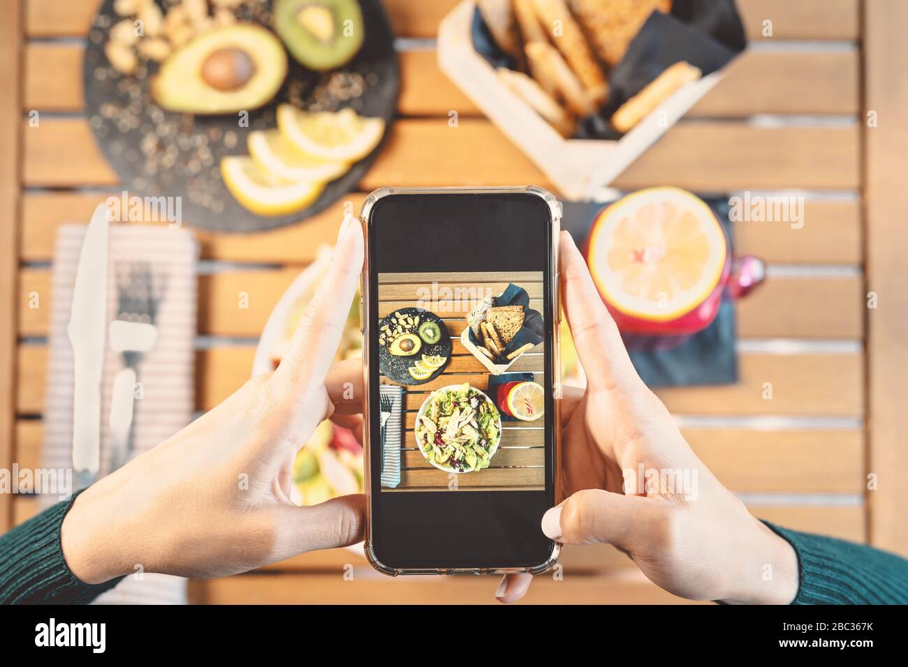Top view female hands taking photo with mobile smartphone on health lunch food - Young girl having fun with new technology apps for social media Stock Photo