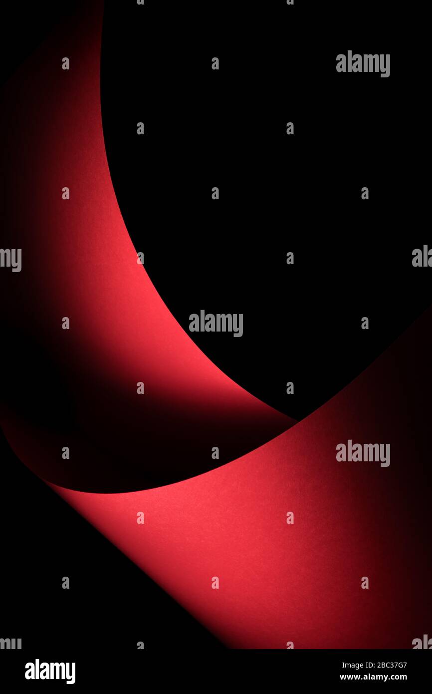 Abstract -  sheets of rolled red paper on a black background. Simple, isolated object with text space perfect for illustrating various concepts. Stock Photo