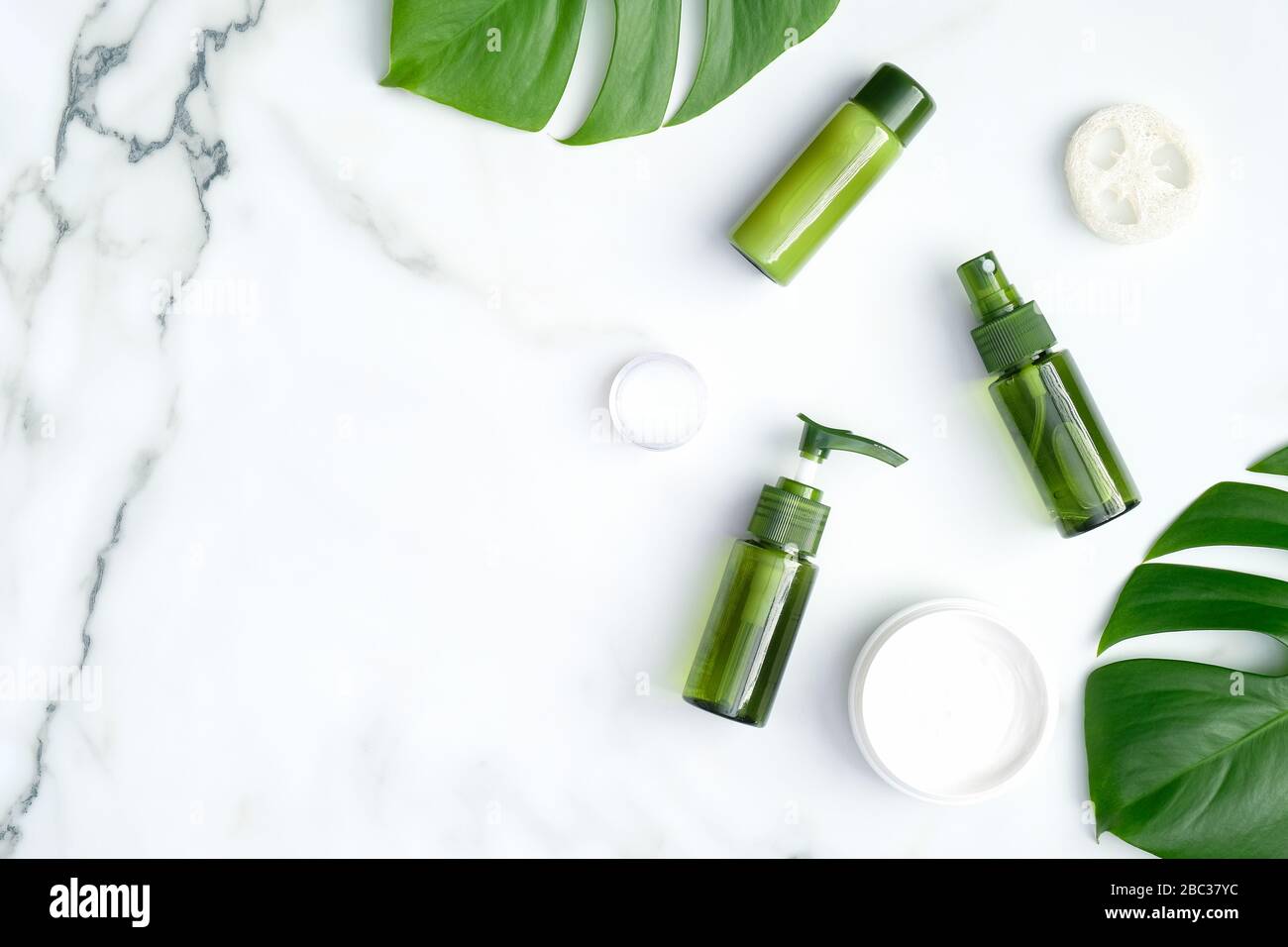 Green cosmetic bottles with monstera tropical leaf on marble background.  SPA natural organic beauty products for skincare, body and hair care. Flat  la Stock Photo - Alamy