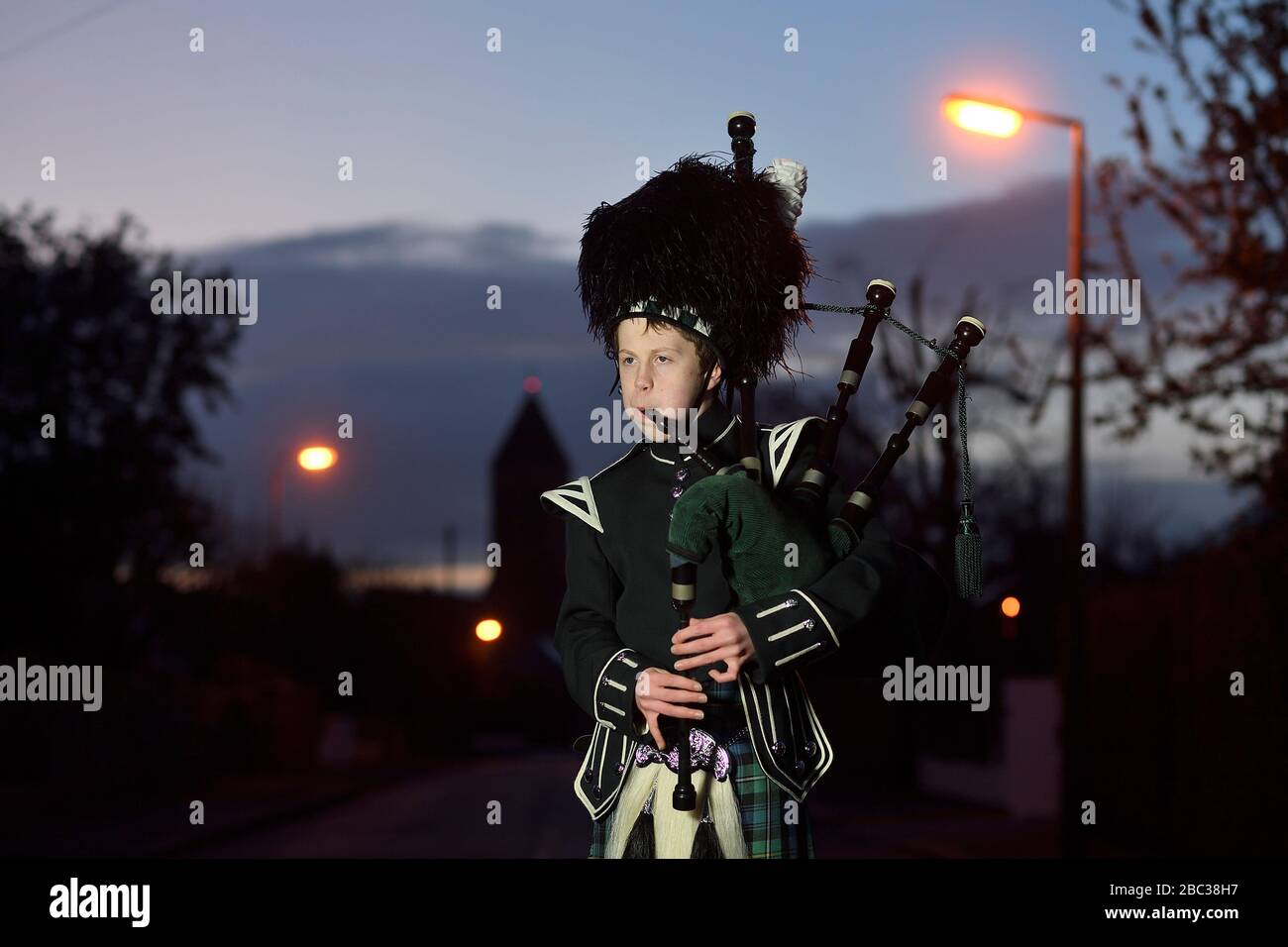 George Orchin (12), a piper in the Campbell College Pipe Band, plays Scotland the Brave outside his neighbour's house in East Belfast, Northern Ireland, during a second Thursday night of 'Clap for our Carers' as people across the country showed their appreciation for all NHS workers who are helping to fight the coronavirus. Stock Photo