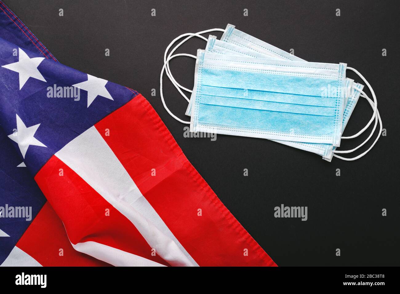 Coronavirus in USA death from coronavirus. Protective surgical face mask on black background with American national flag. Medicine health care Stock Photo