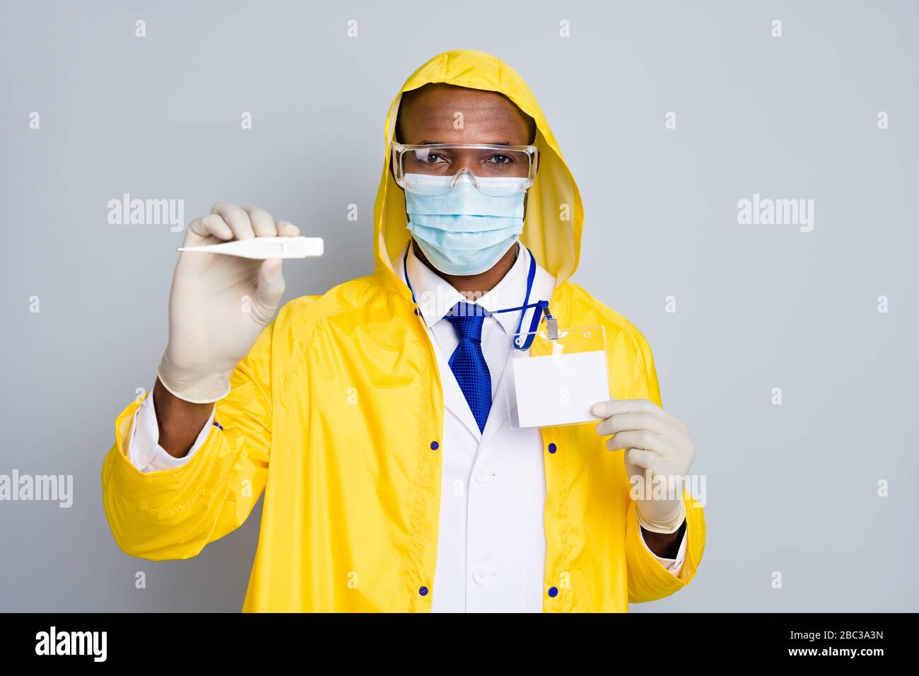 Photo of doc expert dark skin guy virology border department check  temperature tourists travelers thermometer wear epidemic coat hood mask  gloves Stock Photo - Alamy